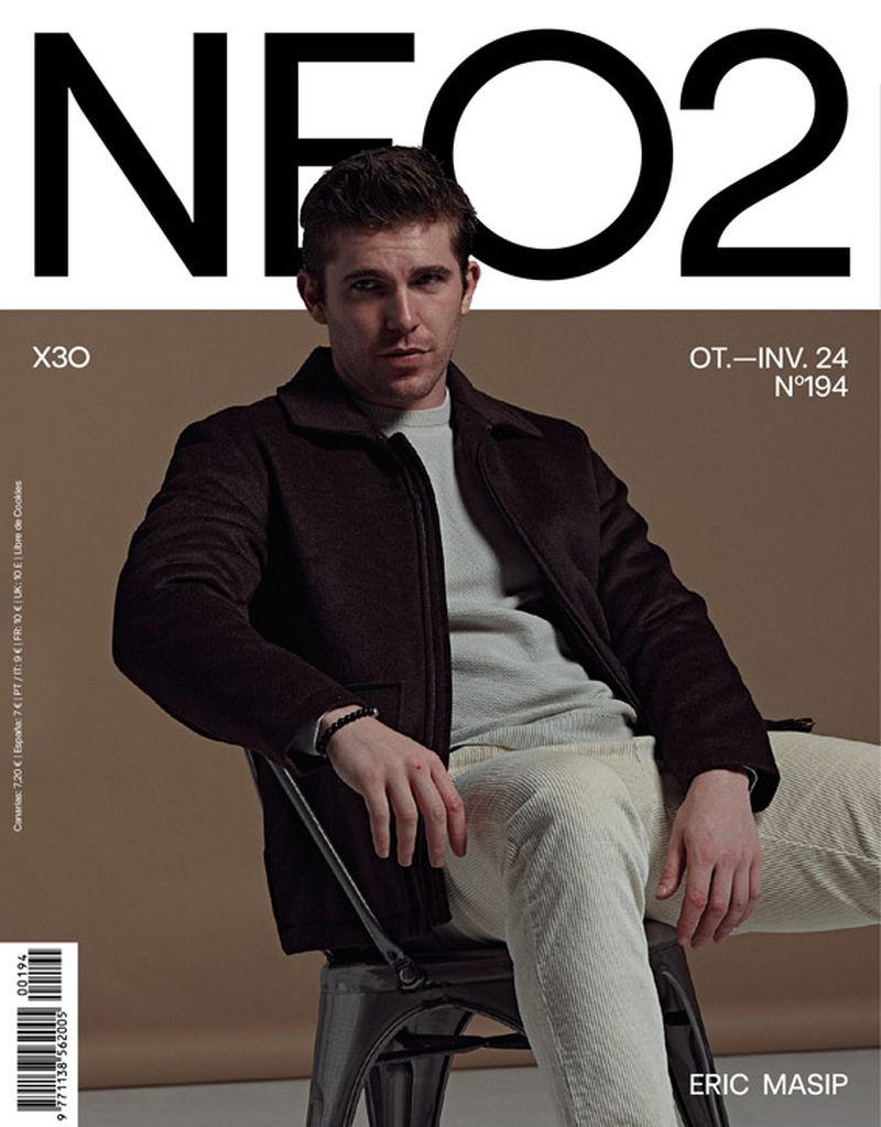NEO2 magazine cover featuring a seated man in a dark jacket and light trousers against a tan backdrop, with bold black lettering.