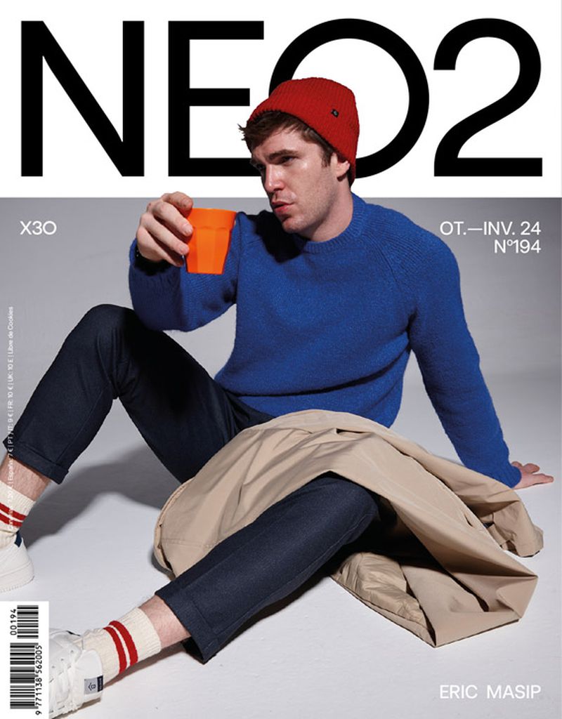 Magazine cover featuring a young adult male model in a blue sweater and beanie, holding an orange cup, with brand text overlay.