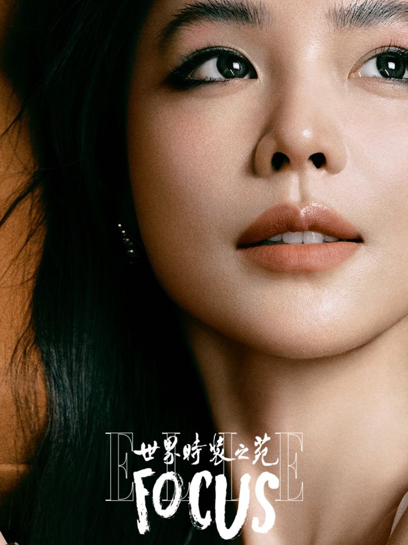 Close-up portrait of an Asian adult female model with dark hair, wearing makeup, posing indoors with a magazine logo in the foreground.