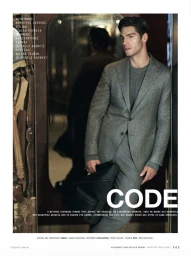 Model Kilian Zeugin posing in a tailored grey wool suit and knitwear while holding a black leather bag for an editorial spread.