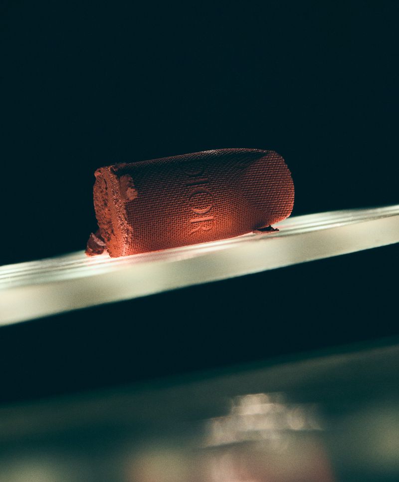 Close-up of a Dior lipstick on a reflective surface, with a dark background creating a dramatic contrast.