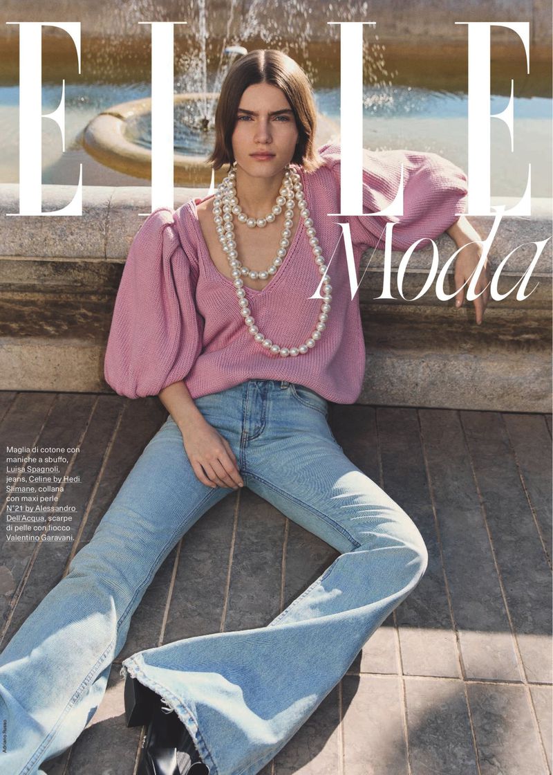 Fashion magazine cover featuring a woman with shoulder-length brown hair wearing a pink sweater, light blue jeans, and pearl necklaces.