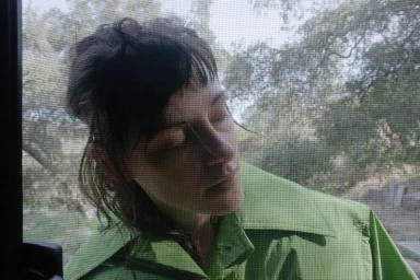 Portrait of Kristen Stewart wearing a green collared jacket viewed through a mesh screen
