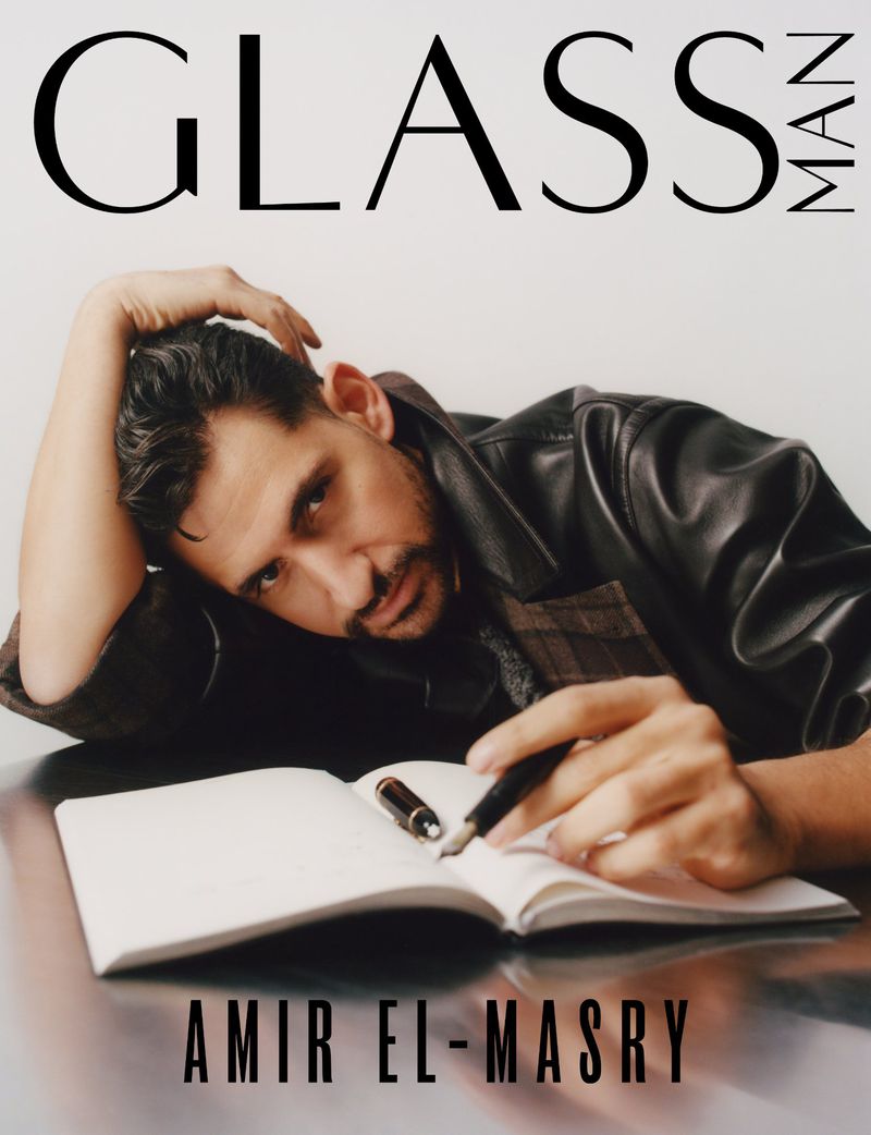 Portrait of Amir El-Masry, pensively writing in a notebook, featured on the cover of Glass Man magazine. He is wearing a black leather jacket.