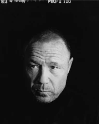 Black and white close up portrait of actor Stephen Graham against a dark background with medium format film rebate visible at the top.