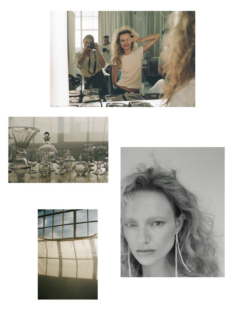 Candid moment of a model getting ready in front of a mirror, with a photographer and a collection of glassware in the background.
