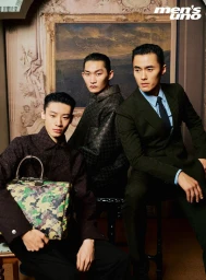 Three Asian male models posing in tailored dark coats and suits against a classical framed landscape painting.