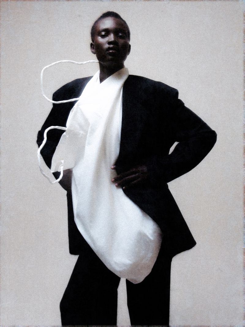 Elegant studio shot of an African American woman in a black suit and white top, captured with soft, diffused lighting on a neutral background.