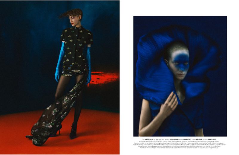 Fashion editorial shot of a woman in a printed short dress and turquoise gloves, with a patterned train, in a dark studio setting.