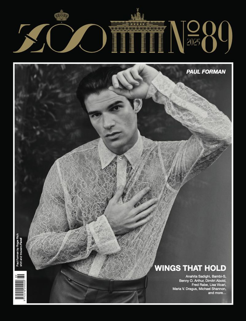 Magazine cover featuring adult male model, Paul Forman, in a lace shirt posing against a blurred, monochromatic background with text overlay.