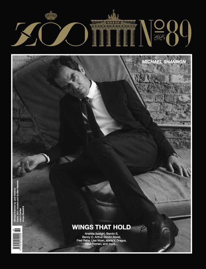 Black and white magazine cover featuring a man in a suit reclining with a brick wall background and the magazine's title at the top.
