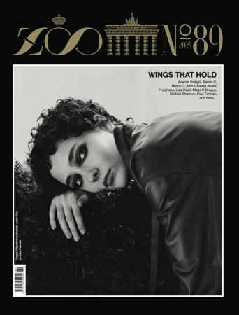 Black and white magazine cover featuring a portrait of a curly-haired person with a leather jacket on a dark, leafy background.