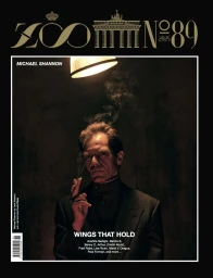 Actor Michael Shannon holding a smoking cigarette under a warm overhead lamp on the cover of Zoo Magazine issue 89.