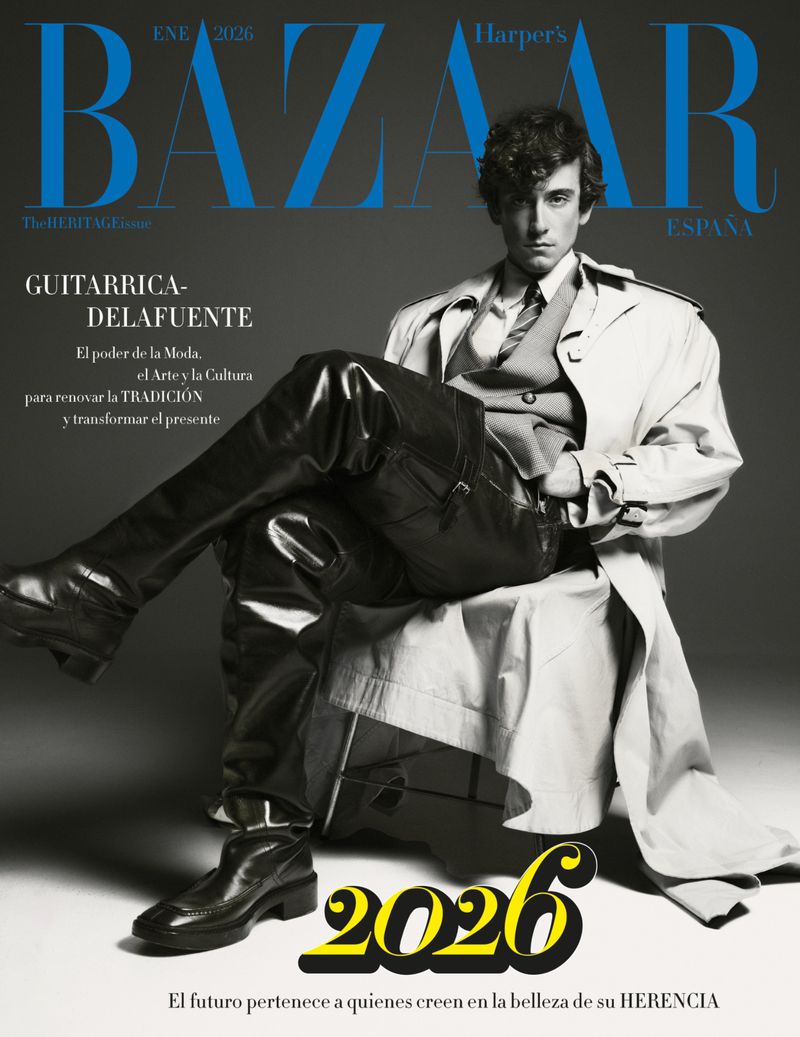 Harper's Bazaar España cover featuring a young adult male model in a trench coat and leather trousers sitting in a studio.