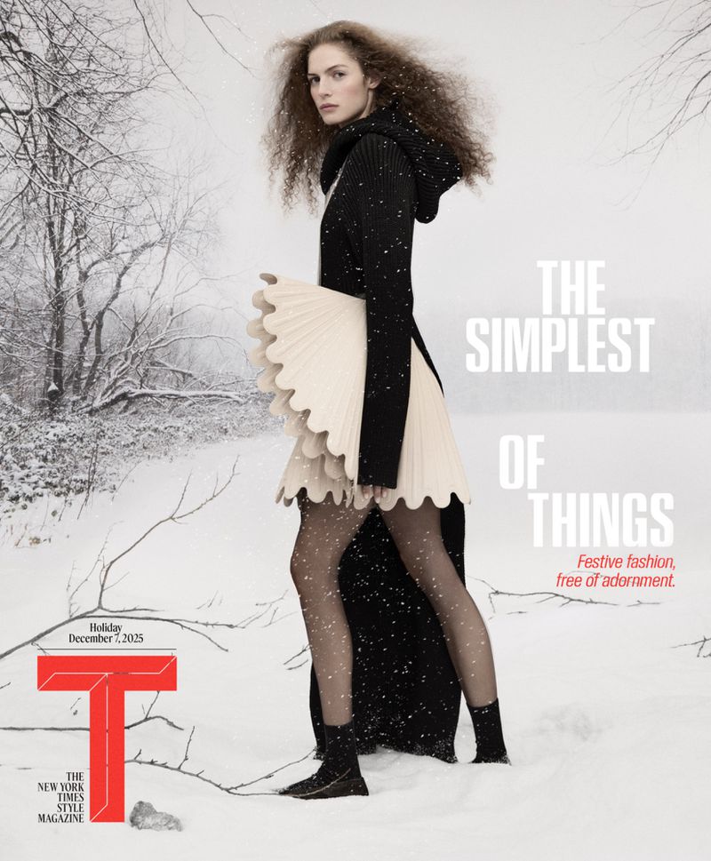 Fashion magazine cover featuring a woman in a black hooded coat and ruffled skirt posing in a snowy landscape with bare trees.