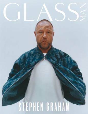 Stephen Graham on a Glass Man magazine cover, wearing a blue patterned bomber jacket, standing against a pale grey backdrop.