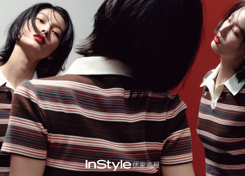 Striking studio portrait of an Asian woman with short black hair and red lipstick, wearing a striped polo shirt in a dynamic composition.