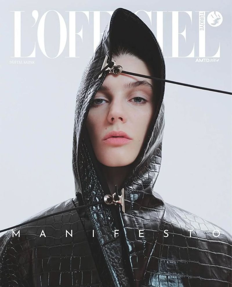Fashion magazine cover featuring a model wearing a textured black hooded jacket with decorative hardware against a light background.