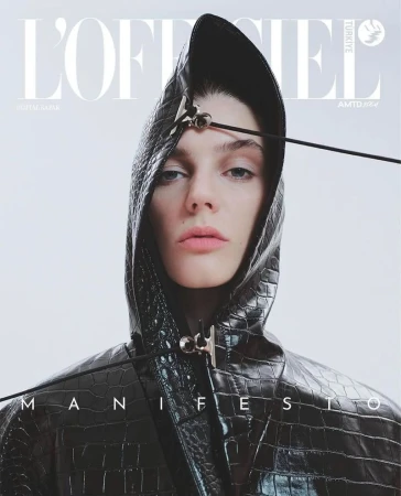 Fashion magazine cover featuring a model wearing a textured black hooded jacket with decorative hardware against a light background.