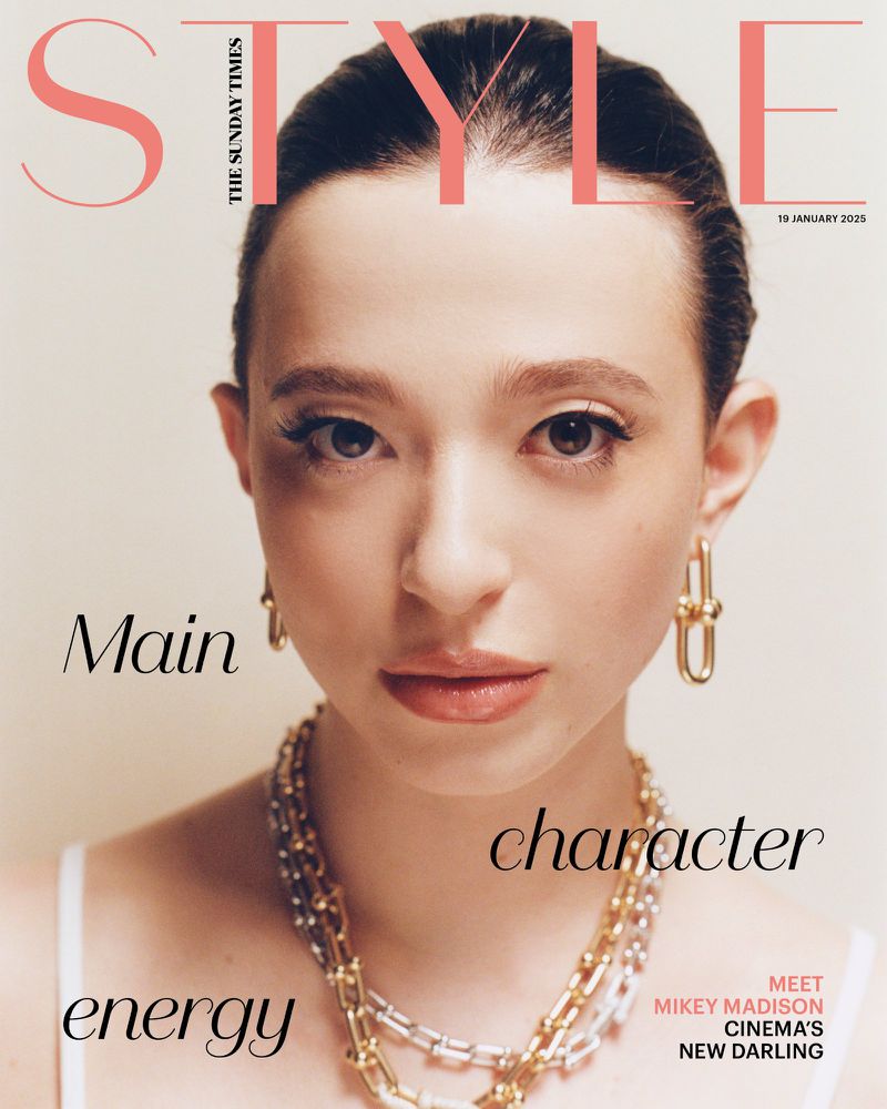 Magazine cover featuring a close-up portrait of a young woman with neutral expression, wearing jewelry, and a peach-toned color grade.