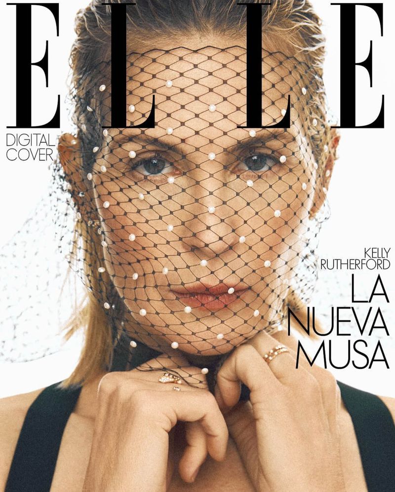 Elle magazine cover featuring a portrait of a woman with a pearl-dotted veil over her face, black top and rings on her fingers.