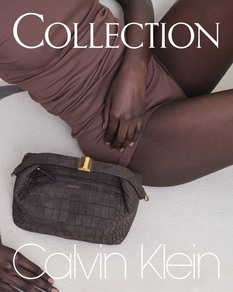 Fashion shot featuring a woman in brown bodysuit lying down, with a brown purse by Calvin Klein. Neutral background, natural lighting.