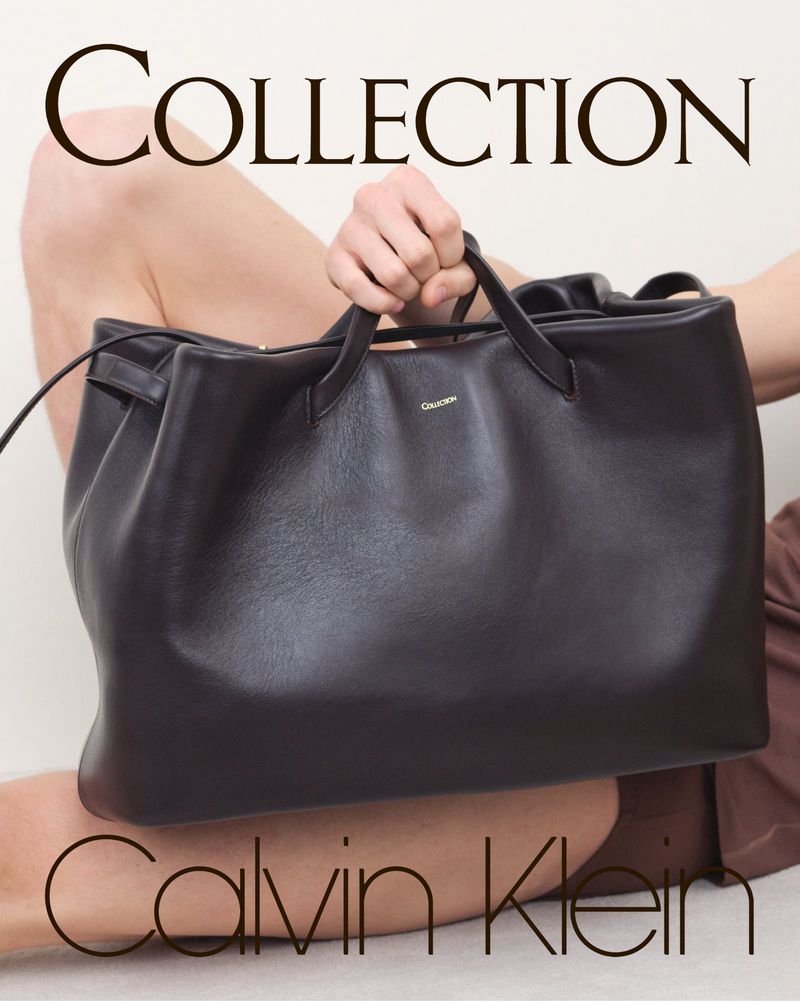 Fashion shot of a model holding a large dark brown leather bag by Calvin Klein, set against a neutral background with visible text.