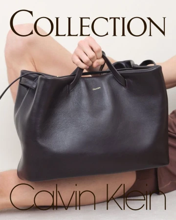 Fashion shot of a model holding a large dark brown leather bag by Calvin Klein, set against a neutral background with visible text.