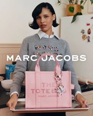 Model holding a tray with a pink Marc Jacobs tote bag in a kitchen setting