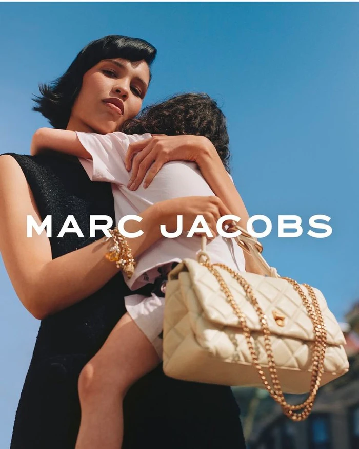 Nara Smith holding a child in a campaign for Marc Jacobs Mothers Day 2025, featuring a quilted cream handbag.