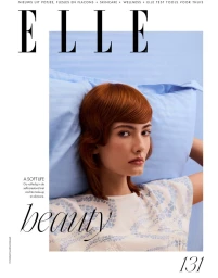 Red-haired model leaning against a blue pillow wearing a patterned top for Elle Netherlands magazine cover.