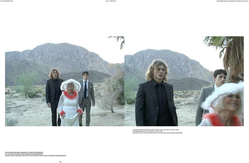 Three people—two young men in suits and an older woman in white—stand in a desert landscape with mountains in the background.