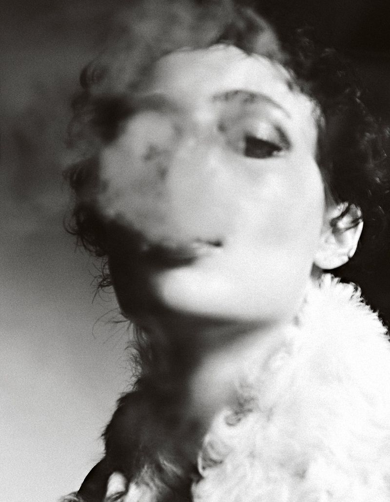 Monochrome portrait of an adult female with smoke obscuring part of her face and wearing a fluffy collar.