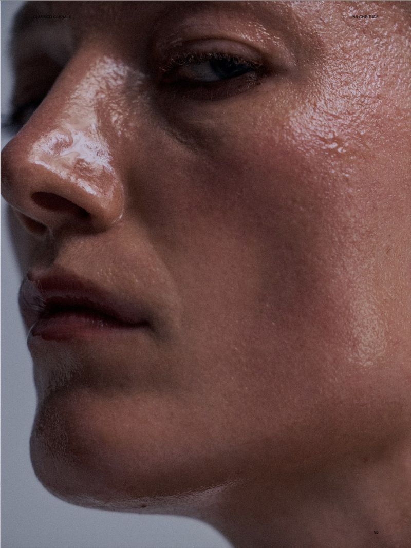 Close-up studio shot of an adult woman with a serious expression. Her skin is shiny and lit dramatically. Focus on natural beauty.