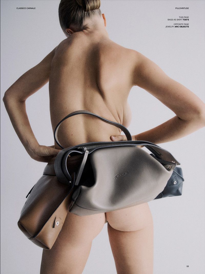 Nude woman with high bun and neutral makeup, wears light grey and brown leather Tod's handbags around her waist, against white background.