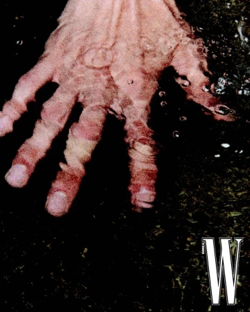 Close-up image of a person's hand under water, creating a distorted and reflective effect, against a dark, textured background.