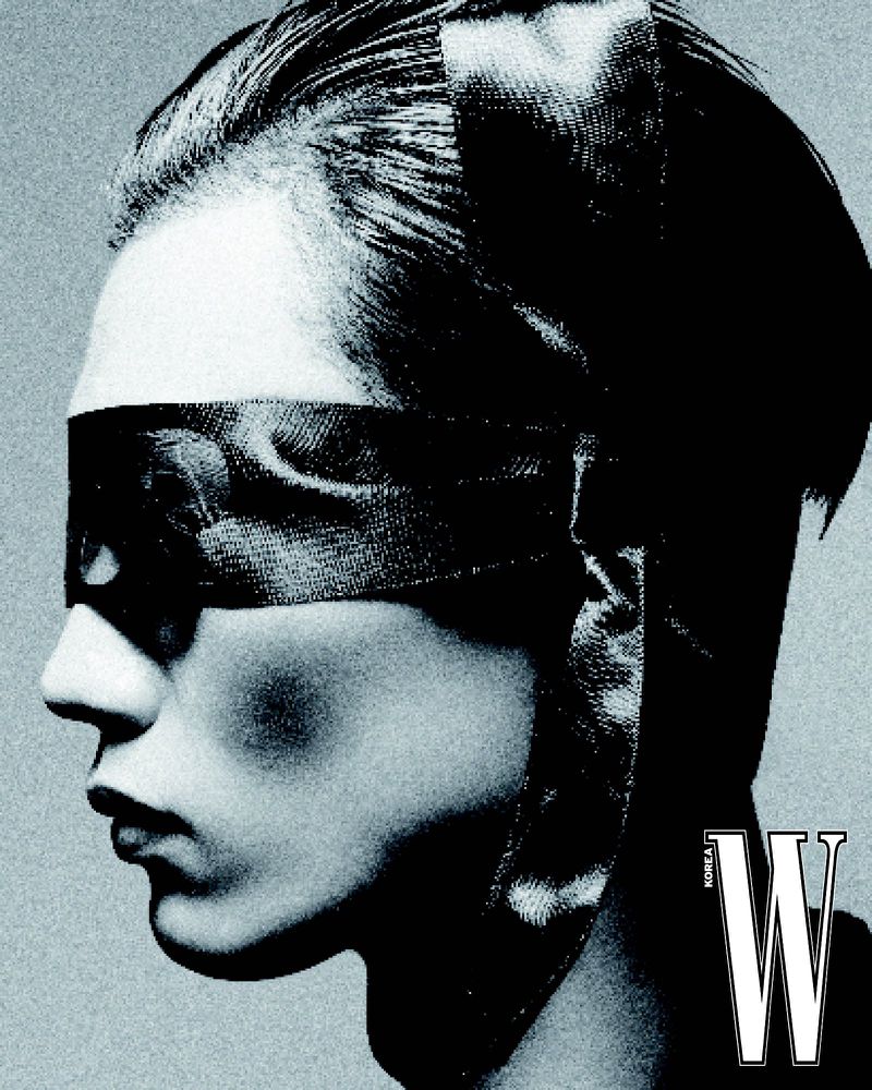 Black and white portrait of a woman with short hair and an eye mask, striking a pose in a photo studio, and a 'W Korea' logo.