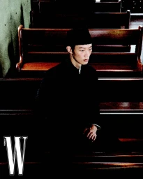 Model Hoyong Kim sitting in dark wooden church pews wearing a black garment and cap for W Korea.