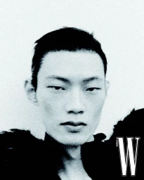 Close-up black and white portrait of model Hoyong Kim wearing a black textured collar against a white backdrop for W Korea.