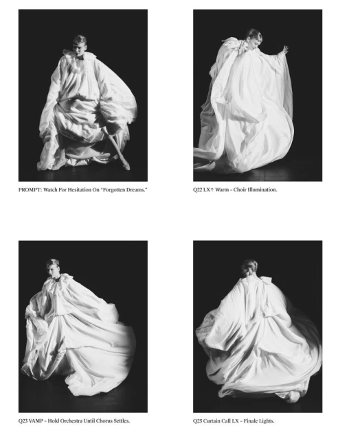 Black and white fashion photography showcases a model in an oversized draped white garment against a dark background, artistic and striking.