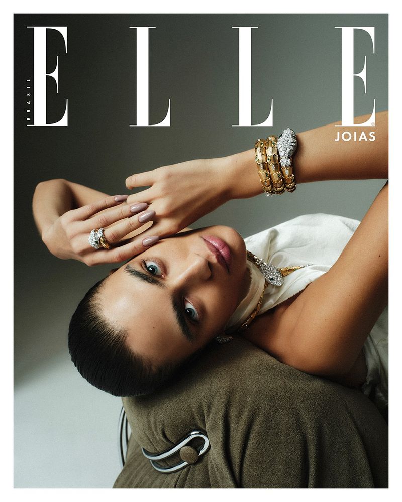 Elle Brazil magazine cover featuring an adult woman with jewelry, wearing a white top, and reclined against a brown cushion.