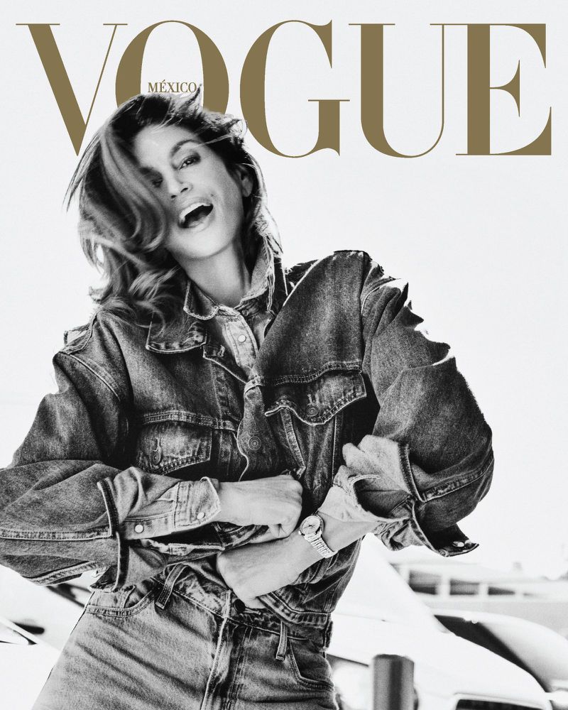 Vogue Mexico cover featuring a cheerful woman in a denim jacket and jeans, her mouth open in a smile, and white architectural background.