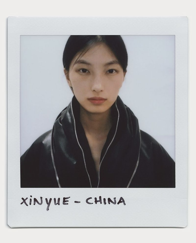Polaroid portrait of a young Asian woman with dark hair, wearing a black jacket, against a plain white background in a white border.