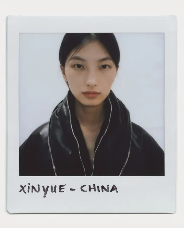 Polaroid portrait of a young Asian woman with dark hair, wearing a black jacket, against a plain white background in a white border.