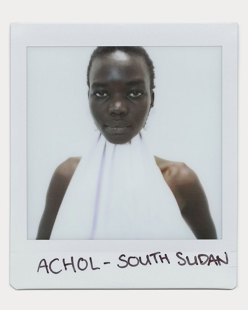 Polaroid portrait of Achol from South Sudan, showcasing a woman with dark skin in a white halter top against a light background.