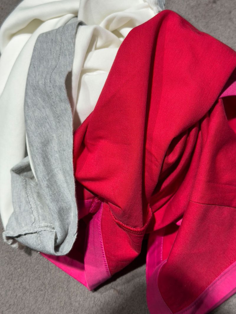 Close-up of a pile of clothing, including a vibrant red top and a gray garment, showcasing textures and folds in the soft fabrics.