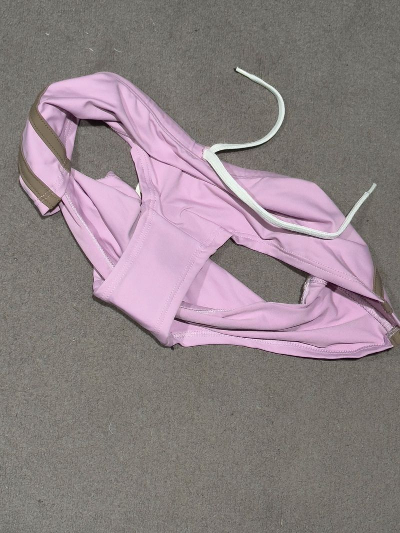 Pink swimsuit bottoms with a white drawstring on a gray surface, showcasing casual swimwear and apparel for fashion or beachwear.