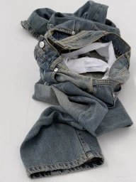 Piled blue denim jeans with white waistband lining resting against a bright white background