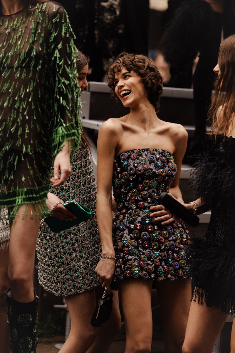 Runway models present embellished mini dresses in an outdoor fashion show, showcasing beauty, style, and fashion forward trends.