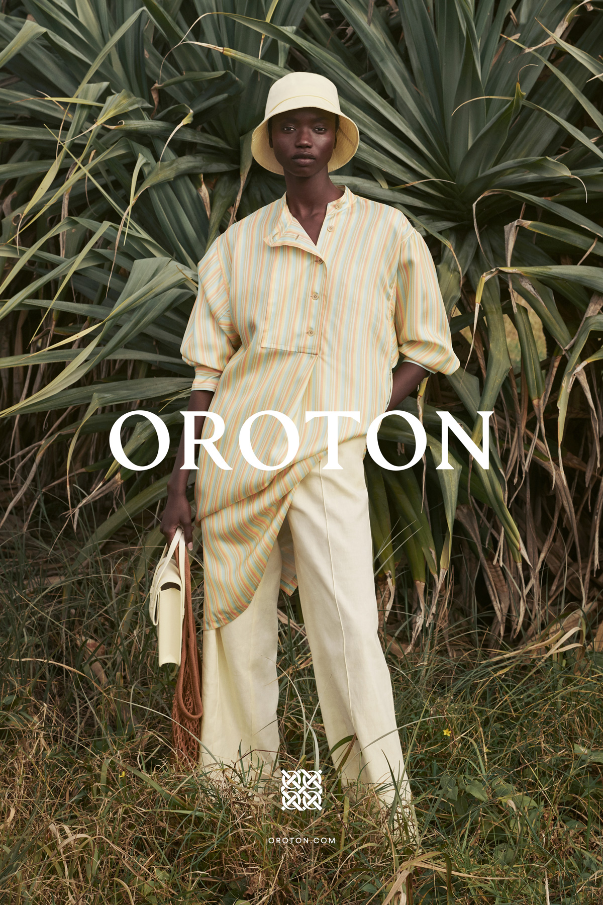 A fashion shot showcases an African woman in a striped top and matching bucket hat, posing outdoors with a neutral bag against green foliage.